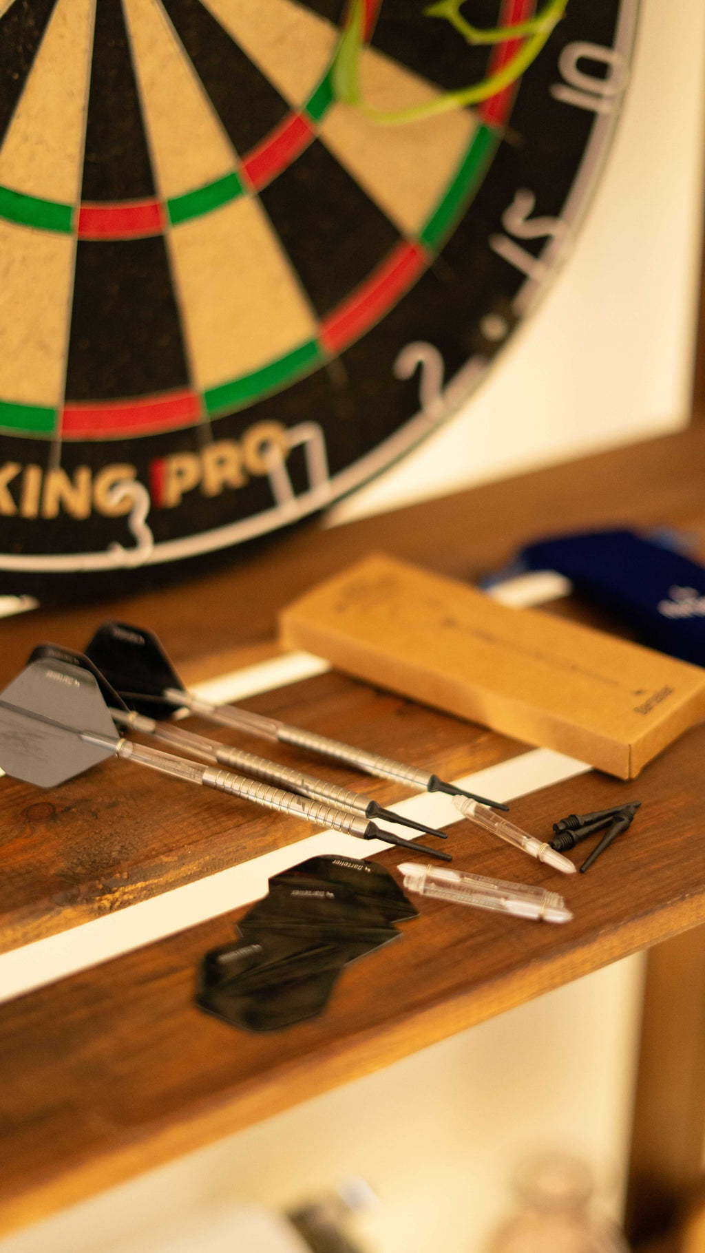 Fléchettes en situation avec le contenu du paquet et une cible en arrière plan